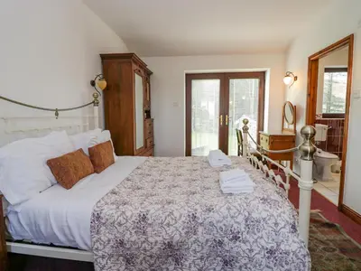 a bedroom with a large bed and a bathroom at Groffa Crag Farmhouse in Lowick Green