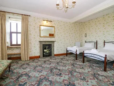a bedroom with two beds and a fireplace at Groffa Crag Farmhouse in Lowick Green