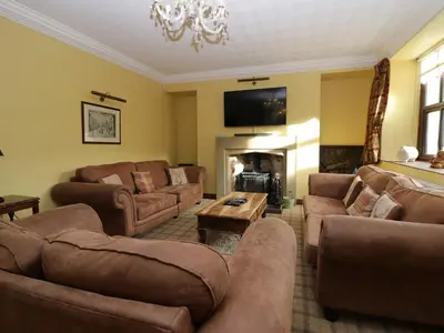 a living room with brown furniture and a fireplace at Groffa Crag Farmhouse in Lowick Green