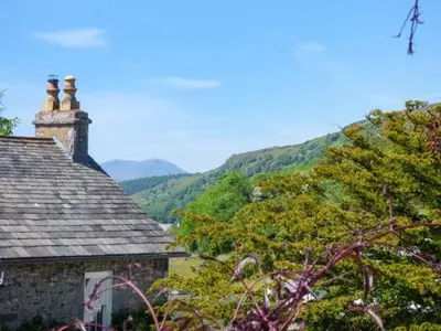 an old stone building with a mountain in the background at High House in High Newton