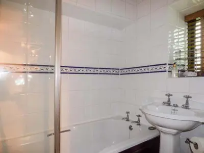 a white bathroom with a sink and a tub and a toilet at High House in High Newton