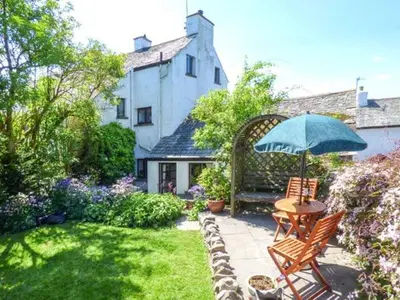 a garden with a table and chairs and an umbrella at High House in High Newton