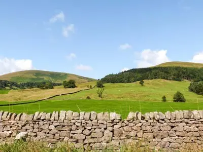 a stone wall in a field with hills in the background at 88 Regent Street in Waddington