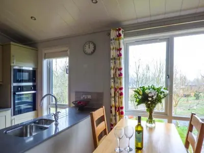 a kitchen with a table with chairs and a clock on the wall at Shepherd Lodge in Cartmel