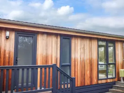a wooden cabin with a porch and a door at Shepherd Lodge in Cartmel