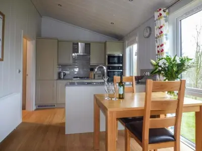 a kitchen with a wooden table and a table and chairs at Shepherd Lodge in Cartmel