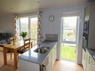 a kitchen with a sink and a table and a clock at Crook Lodge in Cartmel