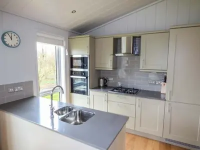 a kitchen with a sink and a clock on the wall at Crook Lodge in Cartmel