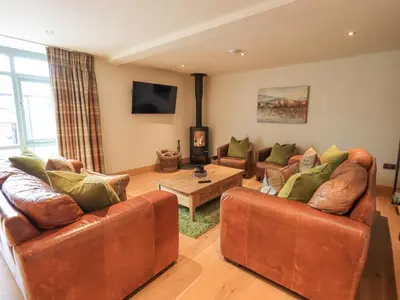 a living room with two leather couches and a table at Yew Cottage in Backbarrow