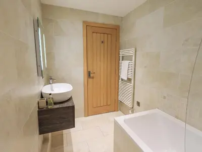 a bathroom with a sink and a tub and a toilet at Yew Cottage in Backbarrow