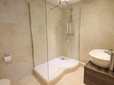 a bathroom with a shower and a toilet and a sink at Yew Cottage in Backbarrow