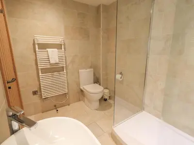 a bathroom with a toilet and a glass shower at Yew Cottage in Backbarrow