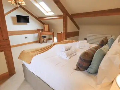 a bedroom with a large bed with towels on it at Yew Cottage in Backbarrow