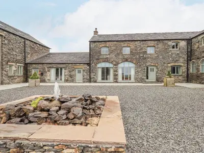 an old stone house with a fountain in front of it at Lime Cottage in Backbarrow