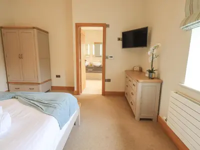 a bedroom with a bed and a dresser and a television at Lime Cottage in Backbarrow