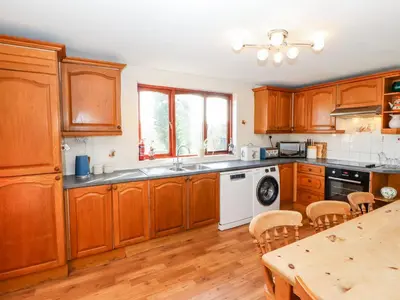 a kitchen with wooden cabinets and a table with chairs at Green Hills Farm in Greenodd