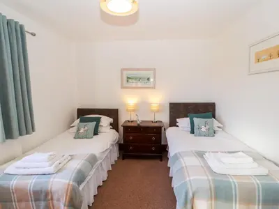 two twin beds in a room with white walls at Green Hills Farm in Greenodd