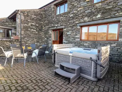 a hot tub in front of a stone building at Green Hills Farm in Greenodd