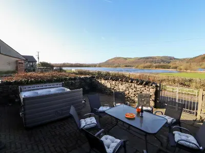 a patio with a table and chairs and a body of water at Green Hills Farm in Greenodd