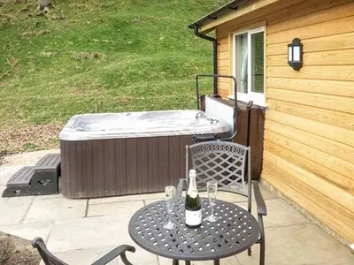 a table with a bottle of wine on a patio at Park Brook Retreat in Scorton