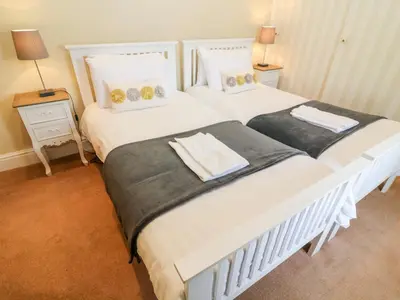 two twin beds in a bedroom with two lamps at Waingate Cottage in Cark