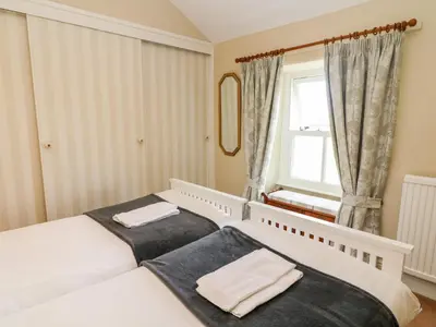 a bedroom with two beds and a window at Waingate Cottage in Cark