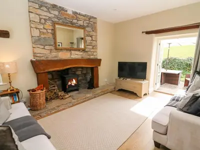 a living room with a stone fireplace and a television at Waingate Cottage in Cark
