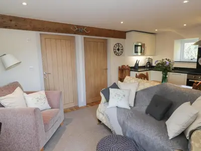 a living room with a couch and a kitchen at The Granary Loft in Sunbrick