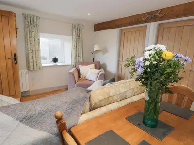 a living room with a couch and a vase of flowers at The Granary Loft in Sunbrick