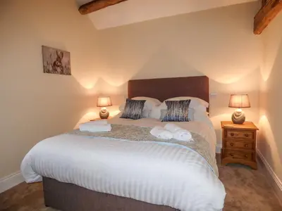 a bedroom with a large bed with two lamps at Cow Hill Laith Barn in Sawley