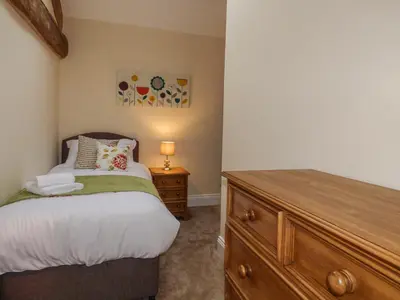 a bedroom with a bed and a wooden dresser at Cow Hill Laith Barn in Sawley