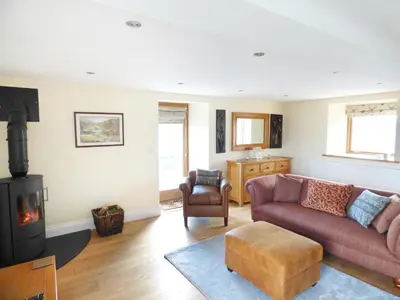a living room with a couch and a stove at Cow Hill Laith Barn in Sawley