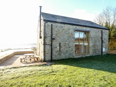 a stone building with a picnic table in front of it at Cow Hill Laith Barn in Sawley