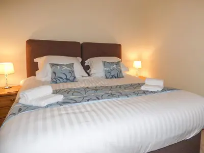 a bedroom with a large bed with two lamps at Cow Hill Laith Barn in Sawley