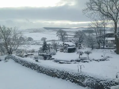 a garden covered in snow with a wall at Saetr Cottage in Harrop Fold