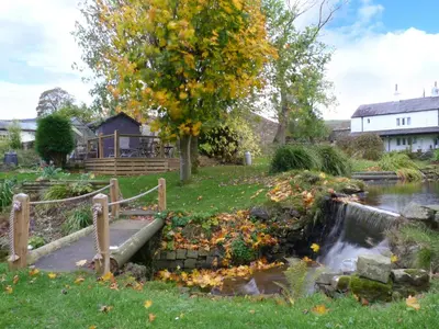 a garden with a small pond and a tree at Saetr Cottage in Harrop Fold