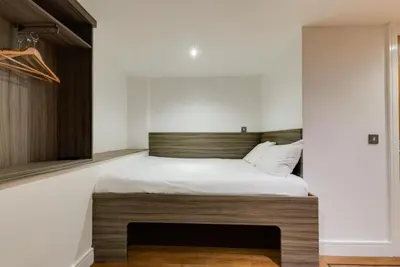 a bedroom with a large bed with a wooden headboard at Print Works Hotel in Liverpool