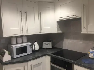 a kitchen with white cabinets and a microwave at Oh So Snug in Whalley