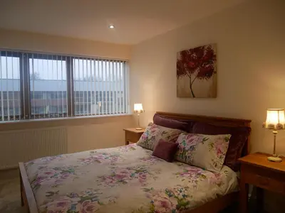 a bedroom with a bed with two lamps and two windows at 8 Swan House in Carnforth