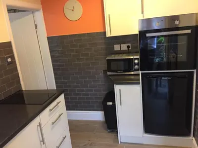 a kitchen with a black refrigerator and a clock on the wall at Cosy Apartment in Private Courtyard in Preston