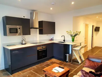 a kitchen with blue cabinets and a living room at The Priory in Scorton