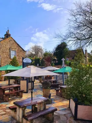 a group of picnic tables with umbrellas on a patio at The Priory in Scorton