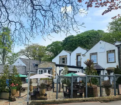 a house with tables and umbrellas in front of it at The Priory in Scorton
