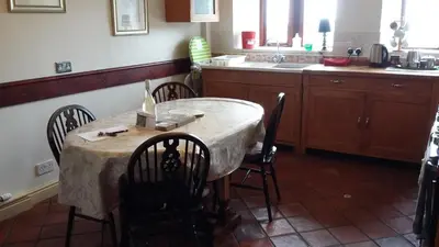 a kitchen with a table with chairs and a sink at Midsummer Barn in Darwen
