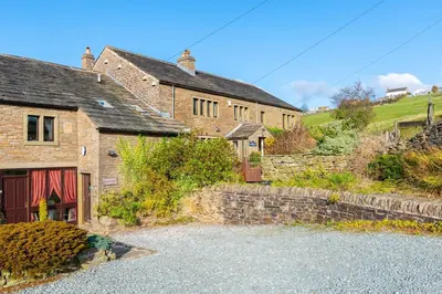 an old stone house with a driveway in front of it at Midsummer Barn in Darwen