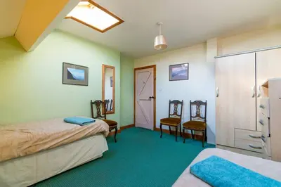 a room with two beds and two chairs in it at Midsummer Barn in Darwen