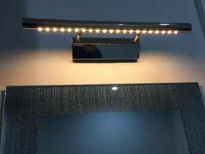 a mirror on a wall with lights above a fireplace at Woodlands Holiday Apartments in Lytham St Annes