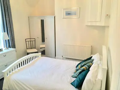 a bedroom with a white bed and a chair at Woodlands Holiday Apartments in Lytham St Annes