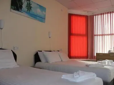 a bedroom with two beds and a red window at The Royal Windsor Hotel in Blackpool