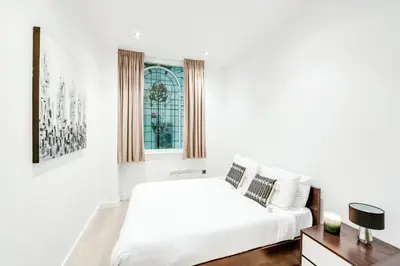 a white bedroom with a bed and a window at Terlon Apartments in Liverpool